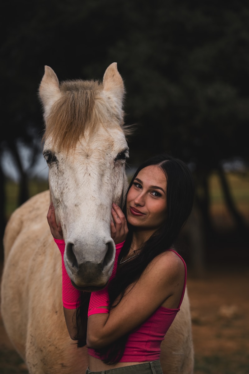 A woman standing next to a white horse